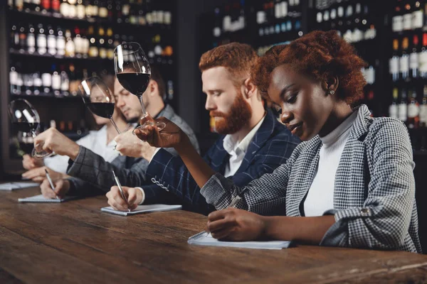 Degustación de vinos tintos en restaurante con sommelier. Grupo de amigos europeos y africanos son el alcohol degustación — Foto de Stock