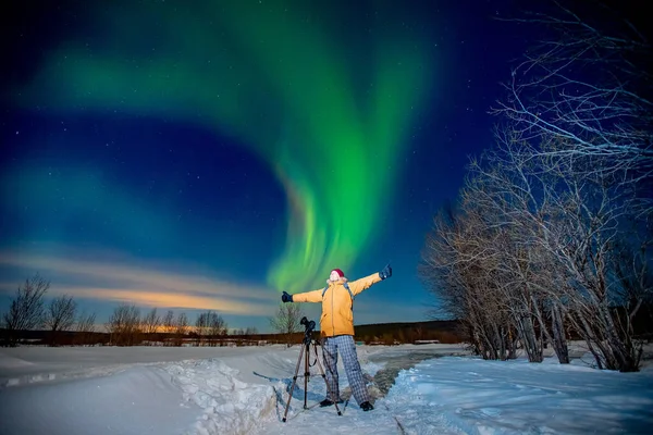Fotógrafo hombre con cámara y trípode fotografías aurora boreal, auroras boreales, auroras boreales verdes. Concepto foto tour a los viajes árticos —  Fotos de Stock