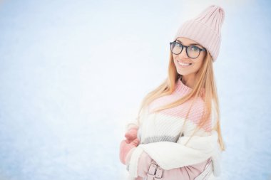 Gözlüklü genç bir kadın ve kışın kar altında örülmüş pembe bir şapka, mutlu bir kız portresi.