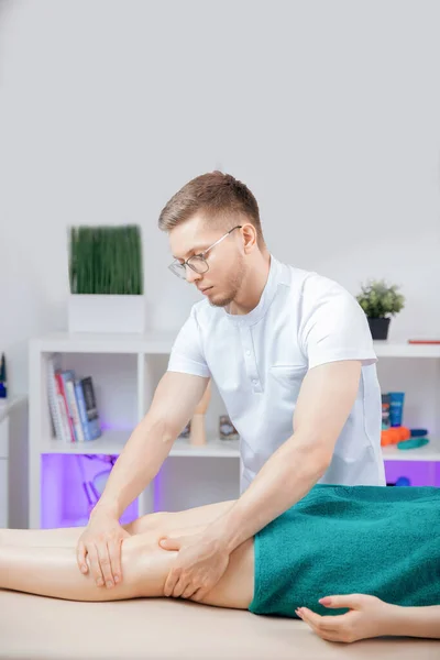 Terapist osteopati kadın sporcunun bacaklarıyla spor masajı yapıyor. — Stok fotoğraf