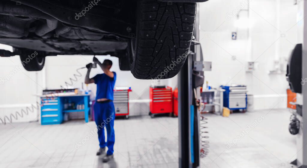 Automobil on lift for wheel suspension maintenance. Car service garage