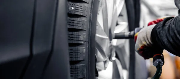 Mechaniker schrauben Räder mit Lichtbanner vom Auto ab. Konzept Austausch von Winter- und Sommerreifen — Stockfoto