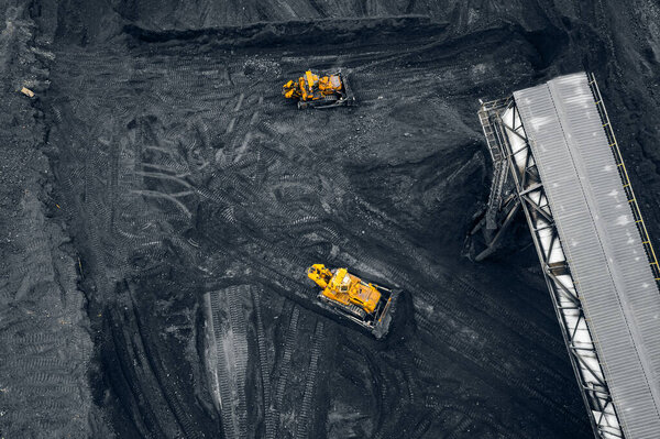 Two yellow excavators Loading coal handling anthracite in an open mine, aerial top view