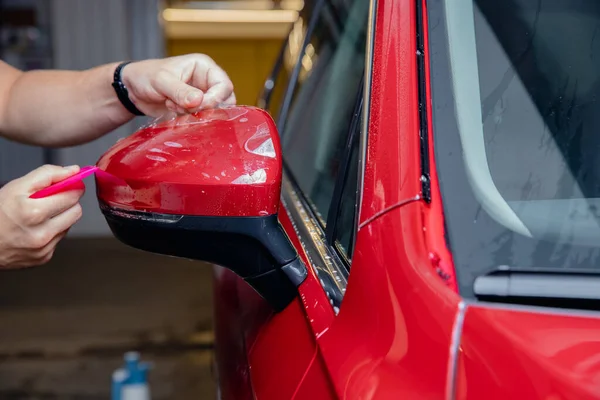 Installa pellicola in vinile per proteggere la vernice specchi laterali auto rossa — Foto Stock