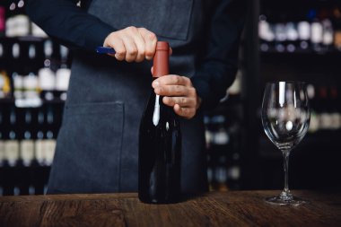 Yakın plan Sommelier, tirbuşonla bir şişe kırmızı şarap açar.