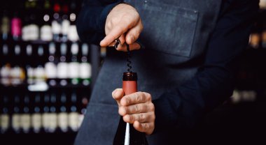 Sommelier bir şişe kırmızı şarabı tirbuşonla açar, konsept pankart tatma