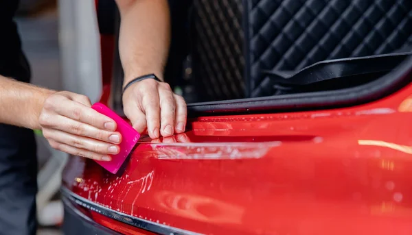 Мастер устанавливает виниловую пленку защиты багажника области загрузки автомобиля краски кузова — стоковое фото