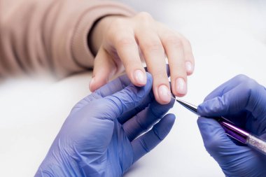 Manikürcü kadın hasta tırnağına jel cilası sürmek için ince fırça kullanır, konsept manikür