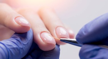 Manikürcü kadın hasta tırnağına jel cilası sürmek için ince fırça kullanır, konsept manikür