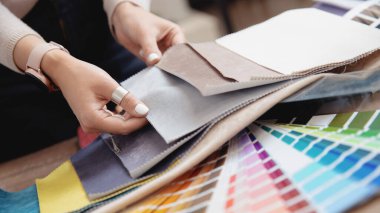 Kadın iç mimar, dekoratör mobilya döşemesi için kumaş, daire projesi için tekstil setinde perde seçiyor.