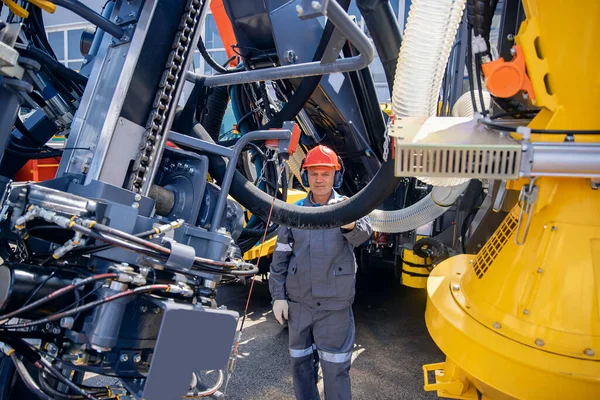Inżynier w twardym kapeluszu i mundurze serwisuje systemy hydrauliczne urządzeń górniczych do zejścia do kopalni — Zdjęcie stockowe