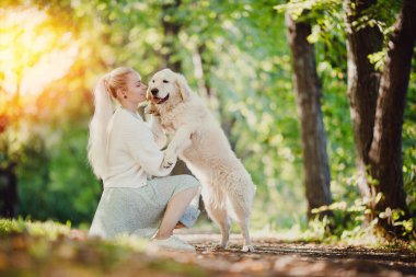 Golden Retriever 'ı olan çekici genç bir kadın. Kız, köpek Labrador arka plan yaz parkına sarılıyor. Arkadaş, arkadaşlık ve insan kavramı.