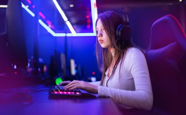 Streamer güzel kız profesyonel oyuncu gülümsemesi çevrimiçi oyunlar oynuyor kulaklıkla bilgisayar, neon rengi