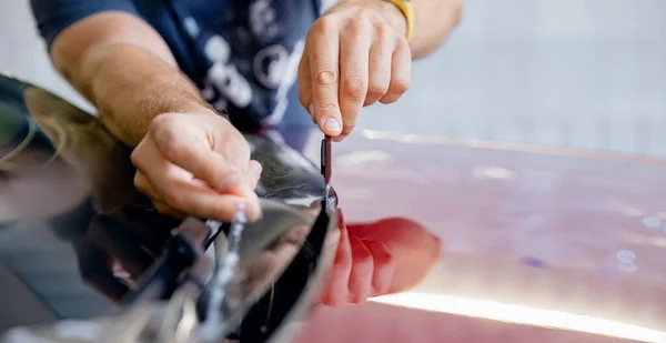 Concetto Protezione trasparente per vernici. Processo di incollaggio cappuccio di auto rossa con pellicola protettiva in vinile da scheggiature e graffi di ghiaia — Foto Stock