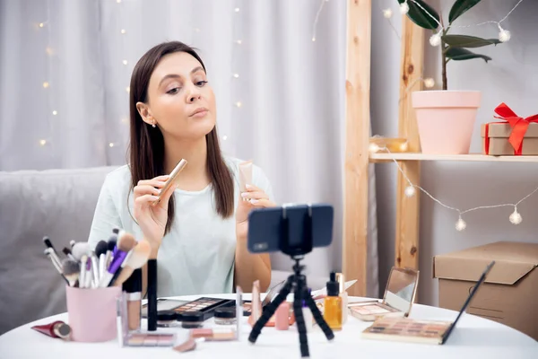 Feliz vlogger mujer está mostrando productos de cosméticos mientras que la grabación de flujo de vídeo en el teléfono. Concepto Influencer blogger beauty blog —  Fotos de Stock