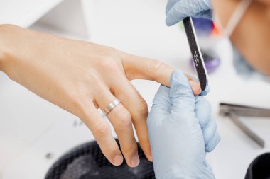 Genç adam güzellik salonunda elleri için profesyonel manikür yaptırıyor.