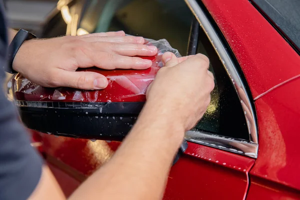 Maestro hombre instala película de vinilo proteger pintura cuerpo lado espejos coche — Foto de Stock