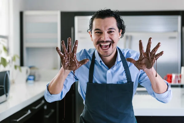 young latin man with mexican chocolate in hands in process of preparing delicious sweets chocolates at kitchen in Mexico Latin America
