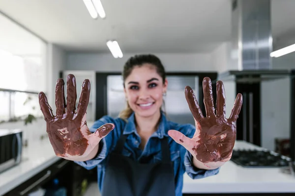 young latin woman with mexican chocolate in hands in process of preparing delicious sweets chocolates at kitchen in Mexico Latin America