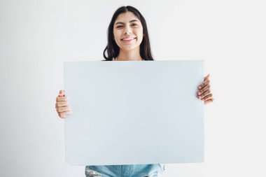 Latin Amerika 'nın beyaz arka planında izole edilmiş boş bir kart tutan genç Latin kadın.