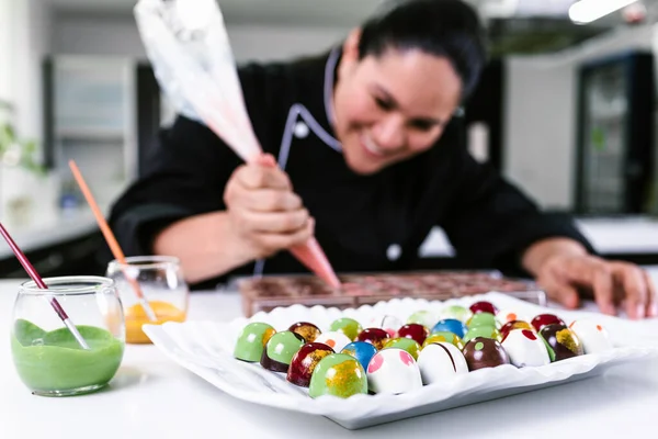 latin woman pastry chef wearing black uniform in process of preparing delicious sweets chocolates at kitchen in Mexico Latin America
