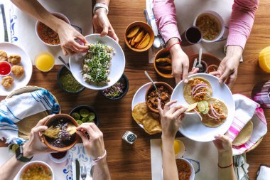 Latin insanlar Meksika yemeği yiyor, ızgara taco, baharatlı salsa, tortilla, bira, abur cubur yiyorlar ve Meksika 'da Latin Amerika' da bir restoranın terasında ahşap masa veriyorlar.