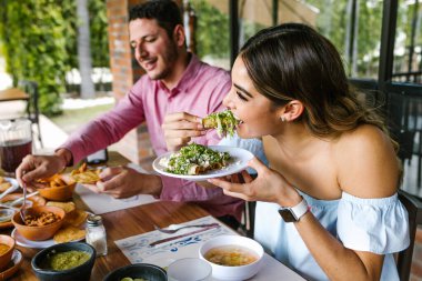 Latin Amerika 'da bir restoranın terasında Meksika tacosu yiyen genç Latin bir kadın yaz günü mutlu hissediyordu.