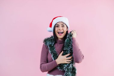 Pembe arka planda noel konseptinde fotokopi alanı olan genç Latin kadın portresi