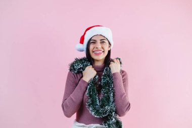 Pembe arka planda noel konseptinde fotokopi alanı olan genç Latin kadın portresi