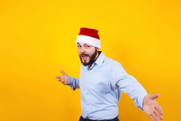 在墨西哥 一个头戴圣诞礼帽 头戴圣诞礼帽的拉丁男人 带着欢乐的笑容 在黄色的背景下惊讶地微笑着 — 图库照片
