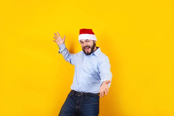 在墨西哥 一个头戴圣诞礼帽 头戴圣诞礼帽的拉丁男人 带着欢乐的笑容 在黄色的背景下惊讶地微笑着 — 图库照片