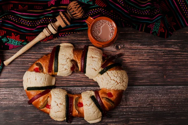 在墨西哥 拉丁美洲的木桌上放着红葡萄酒热巧克力的Rosca Reyes或Epiphany蛋糕和黏土杯 — 图库照片