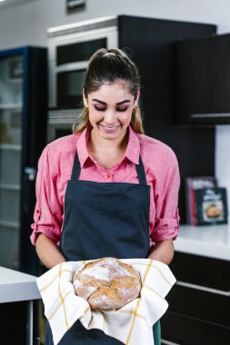 Latin Amerikalı genç bir kadın Meksika 'da mutfakta bir parça ekmek tutuyor.