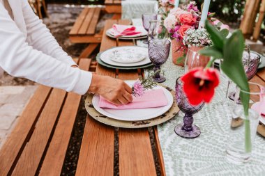 Latin Amerika 'daki düğün resepsiyonu için hazırlanmış çiçek, bardak ve tabakları masaya koyun.