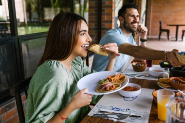 Latin Amerika 'da bir restoranın terasında Meksika tacosu yiyen genç Latin bir kadın yaz günü mutlu hissediyordu.