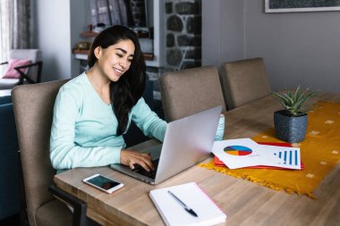 Latin Amerika 'da evde dizüstü bilgisayarla çalışan ya da okuyan genç İspanyol kadın.