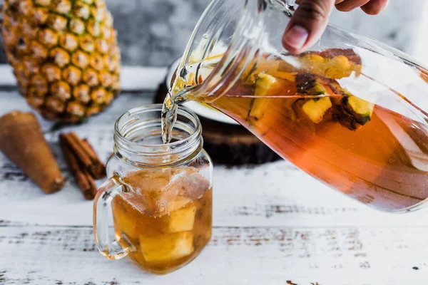 Tepache mexican Fermented pineapple drink and hand holding a Jar with kombucha homemade probiotic superfood sliced pineapple beverage in Mexico city