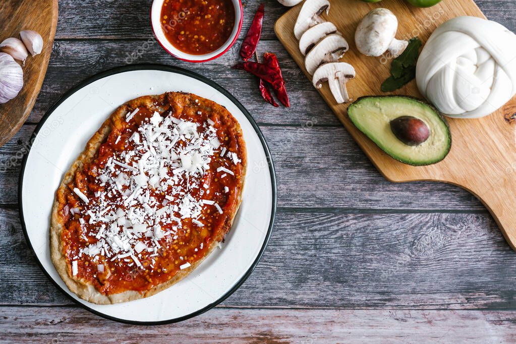 Mexican breakfast memela, sope, quesadilla made of tortilla with red sauce, cheese and onion traditional food from Puebla City in Mexico