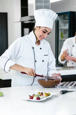 Latin kadın pasta şefi üniforma giyiyor, elinde bir kase tutuyor Meksika 'da mutfakta lezzetli çikolatalar hazırlıyor.