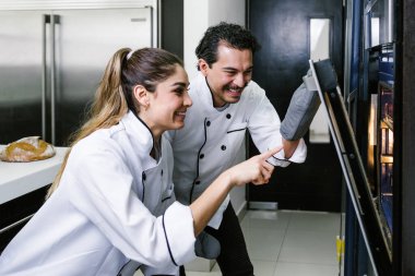 Latin Amerikalı genç çift, kadın ve erkek fırıncılar Meksika 'da mutfakta kruvasan ve ekmek pişiriyorlar.