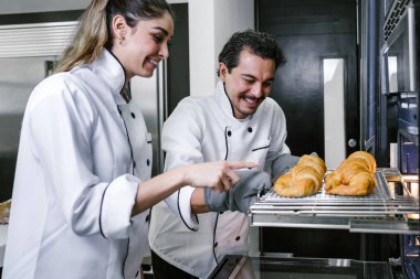 Latin Amerikalı genç çift, kadın ve erkek fırıncılar Meksika 'da mutfakta kruvasan ve ekmek pişiriyorlar.