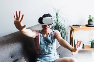 Latin Amerikalı genç bir kadın Meksika 'da sanal gerçeklik gözlüğü kullanıyor ve oynuyor.