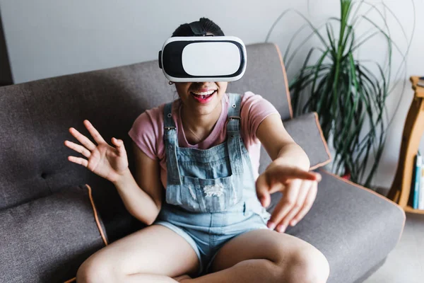 Latin Amerikalı genç bir kadın Meksika 'da sanal gerçeklik gözlüğü kullanıyor ve oynuyor.