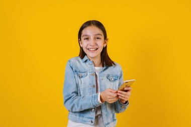 Latin kız, Meksika Latin Amerika 'da sarı arka planda cep telefonu tutuyor.