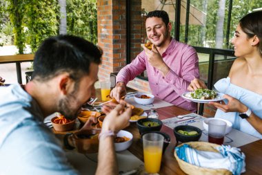 Latin Amerika 'nın Meksika restoranının terasında geleneksel Meksika yemeklerini yiyen bir grup Latin arkadaş.