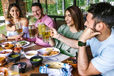 Latin Amerika 'nın Meksika restoranının terasında geleneksel Meksika yemeklerini yiyen bir grup Latin arkadaş.