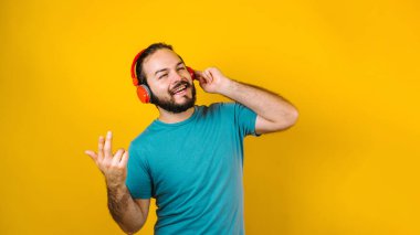 Latin Amerika 'nın sarı arka planında, kulaklıklı, dans eden ve müzik dinleyen İspanyol bir gencin portresi.