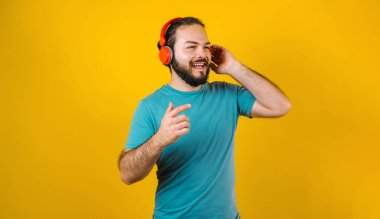 Latin Amerika 'nın sarı arka planında, kulaklıklı, dans eden ve müzik dinleyen İspanyol bir gencin portresi.