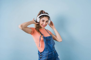 Genç esmer Latin kız. Kulaklıklı müziği dinle ve Meksika Latin Amerika 'da mavi arka planda kopyala.