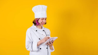 Latin Amerikalı genç bayan aşçı elinde not defteri ve Meksika Latin Amerika 'da sarı arka planda kopya alanı tutuyor.